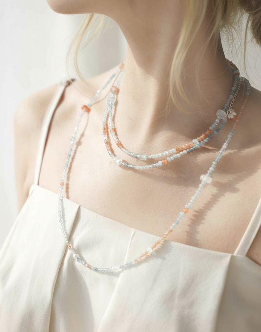 Person wearing a layered beaded necklace with a plain background