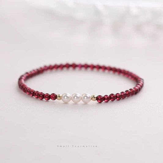 Beaded bracelet with red beads and white pearls on a light background