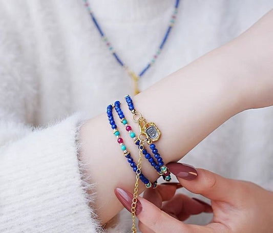 Close-up of a wrist with colorful beaded bracelets and a gold watch strap.