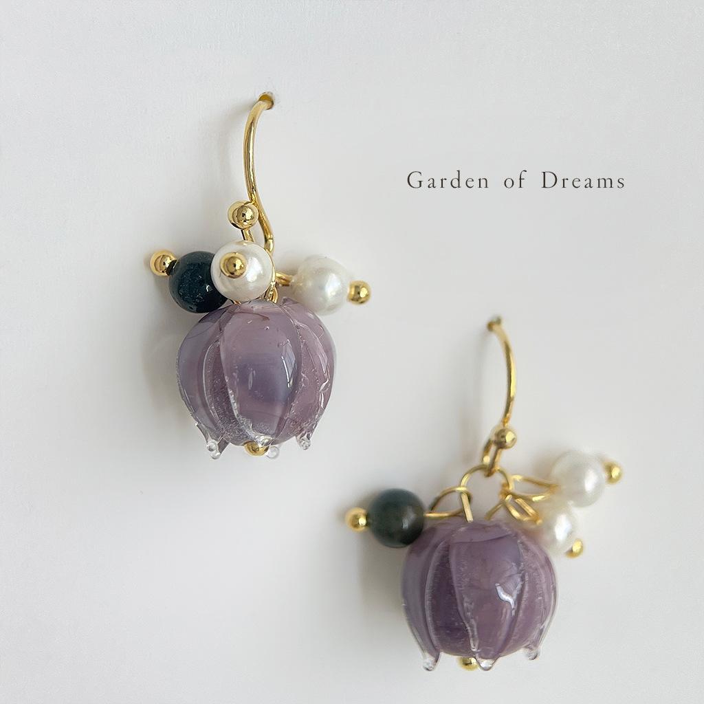 Pair of earrings with purple glass beads and gold accents on a white background.