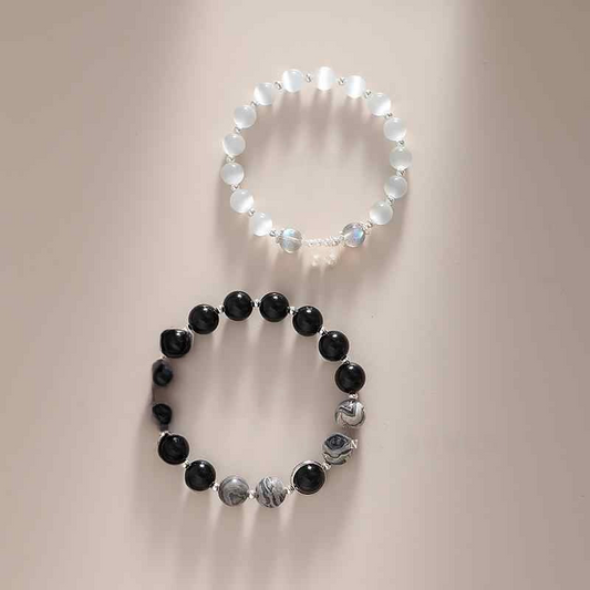 Two bracelets, one black and one white, on a neutral background.