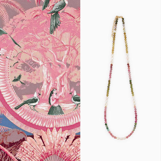 Beaded necklace on a white background with a pink patterned fabric in the corner