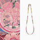 Beaded necklace on a white background with a pink patterned fabric in the corner