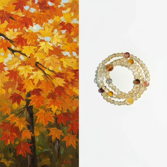 Stack of beaded bracelets on a white background with an autumn leaf painting on the left.