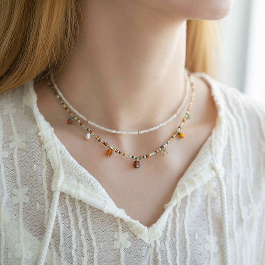 Close-up of a person wearing a delicate necklace with small beads.