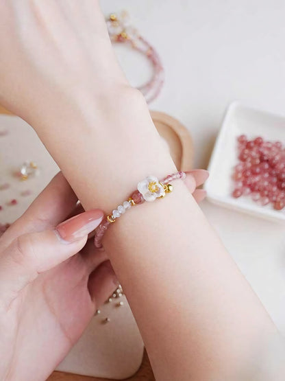 Close-up of a hand wearing a pink beaded bracelet with a small decorative element.