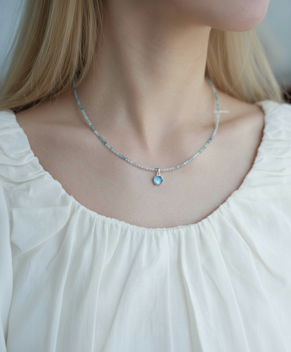 Necklace with a pendant worn by a person in a white blouse