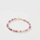 A Super Seven Crystal Bracelet with faceted beads in multiple colors and a gold-plated clasp, displayed against a white background.