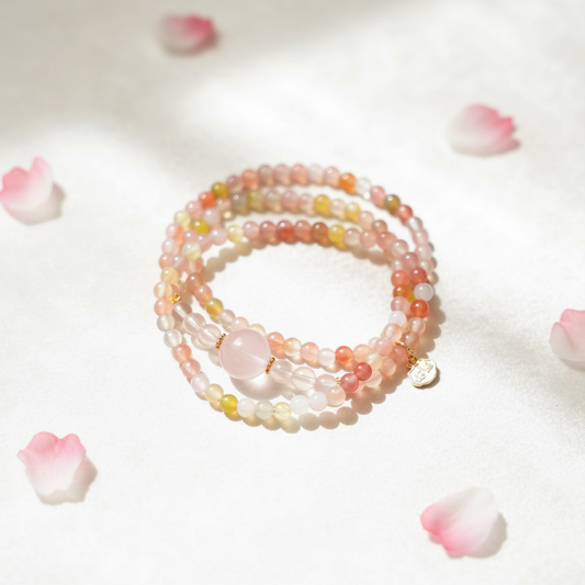 Set of beaded bracelets on a white surface with pink flower petals