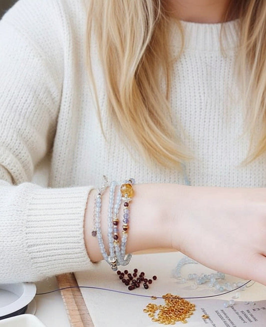 Person wearing multiple bracelets on a light background