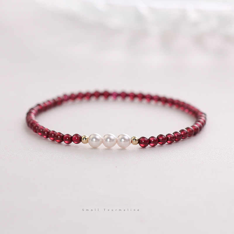 Beaded bracelet with red beads and white pearls on a light background