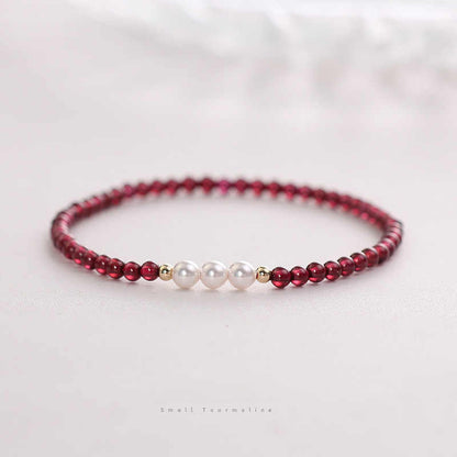 Beaded bracelet with red beads and white pearls on a light background