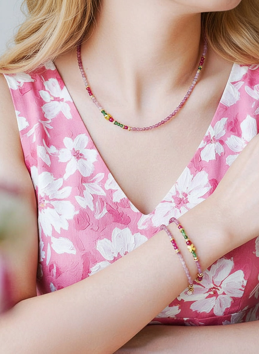 Person wearing a pink floral dress with a colorful beaded necklace and bracelet.