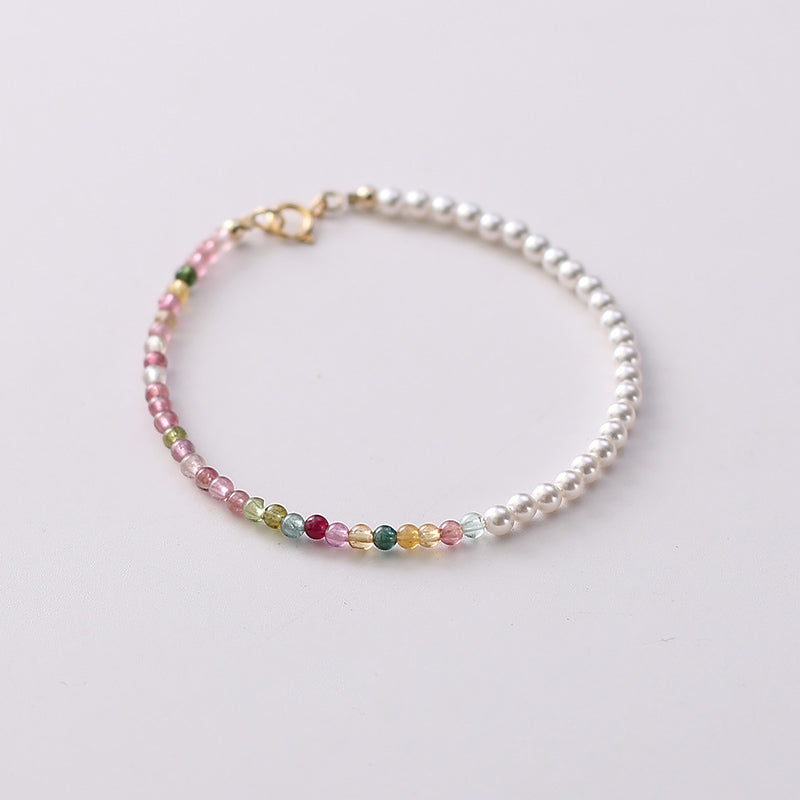 Bracelet with white pearls and multicolored gemstones on a light background
