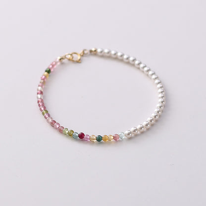 Bracelet with white pearls and multicolored gemstones on a light background