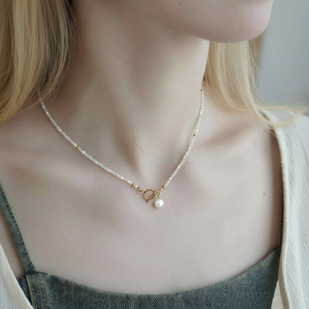 Pearl necklace with a heart charm worn by a person