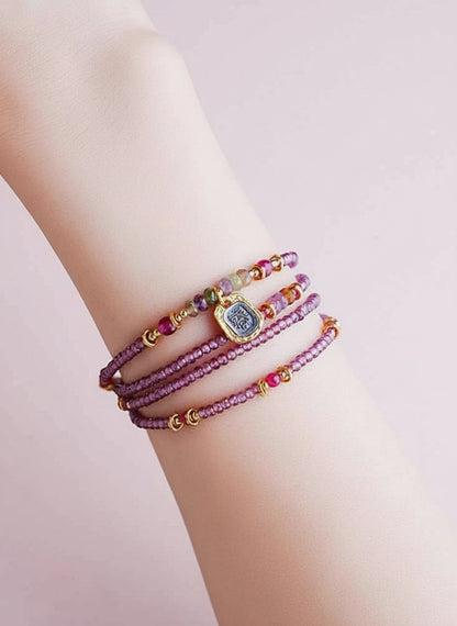 Multicolored beaded bracelets on a wrist against a light background