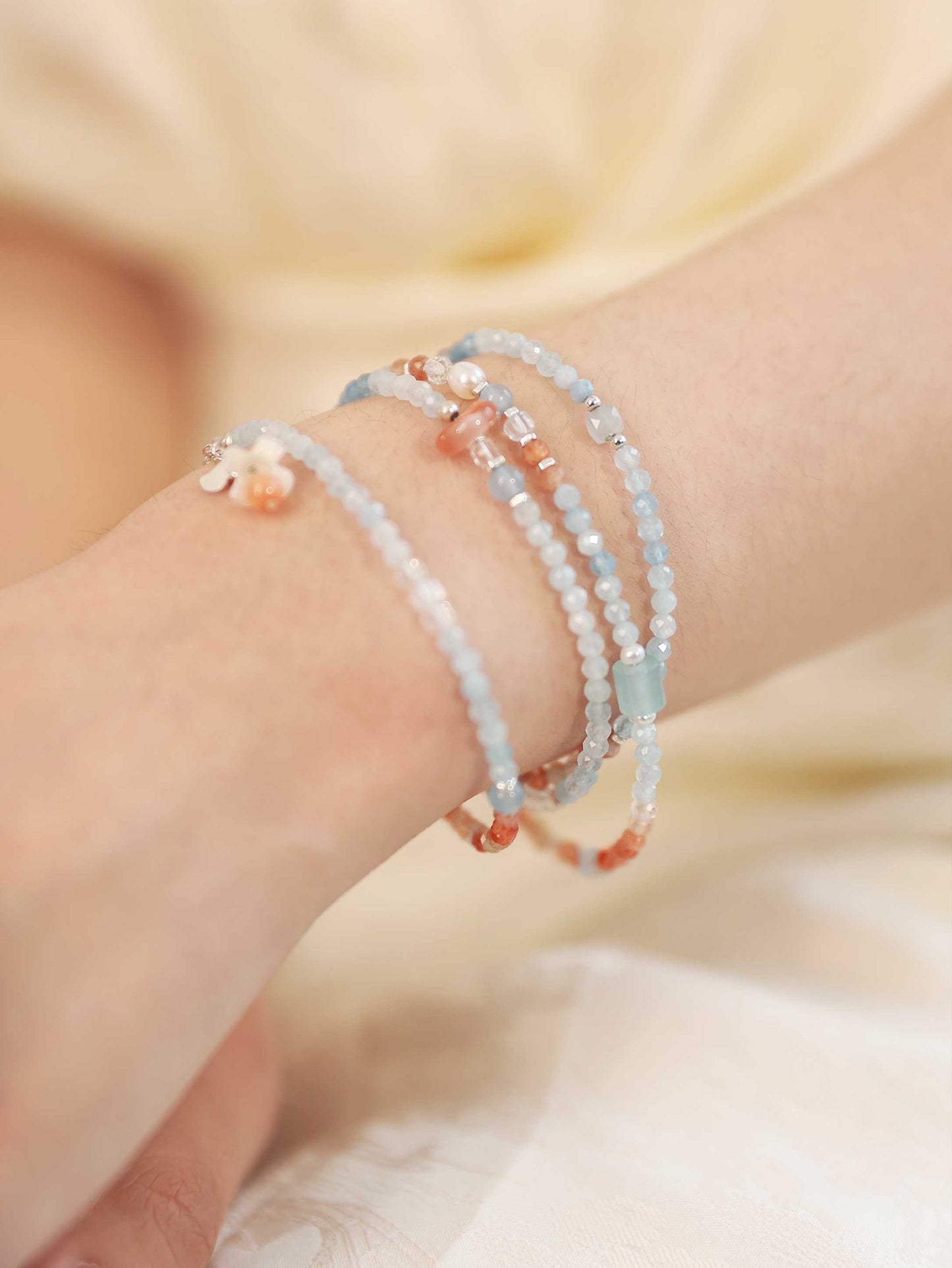 Close-up of a wrist wearing multiple beaded bracelets on a blurred background