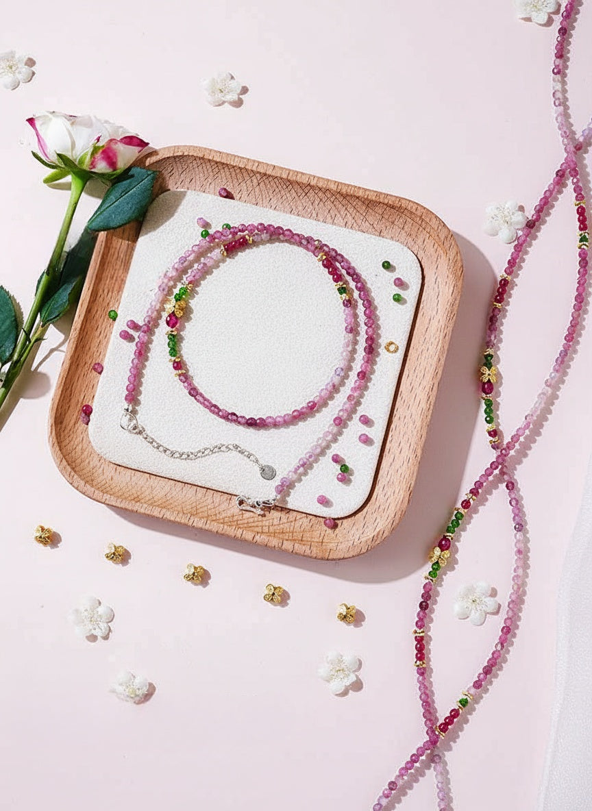 Necklace on a wooden tray with flowers and small decorative items on a light pink background