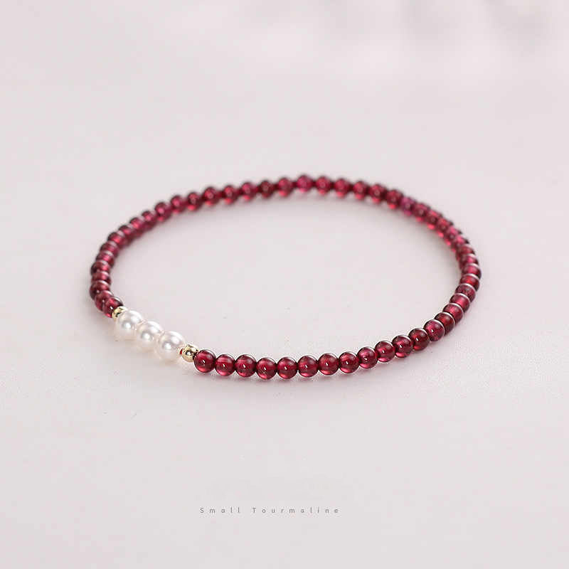 Bracelet with red beads and a pearl on a light background