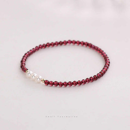 Bracelet with red beads and a pearl on a light background