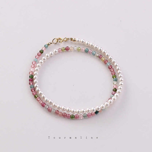 A double strand bracelet with one layer of multicolored natural tourmaline beads and another layer of luminous imitation pearls, featuring a gold-plated clasp.