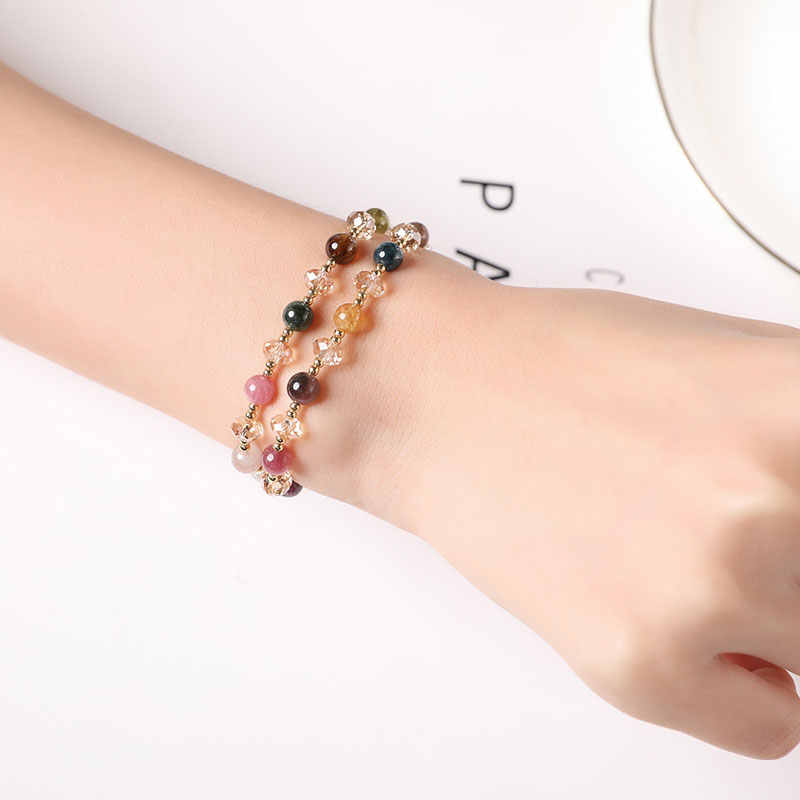 Multicolored beaded bracelet on a wrist against a white background