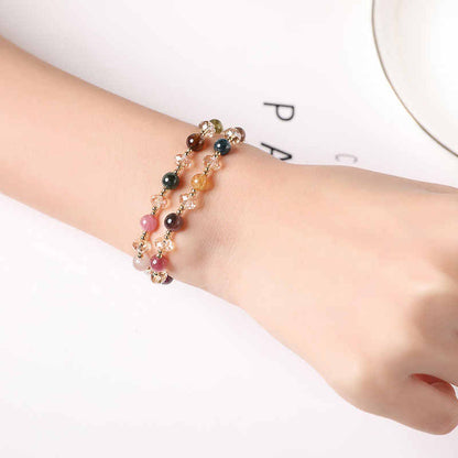 Multicolored beaded bracelet on a wrist against a white background