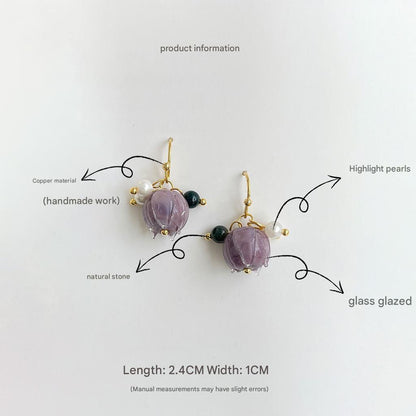 Pair of earrings with purple stones and gold accents on a white background