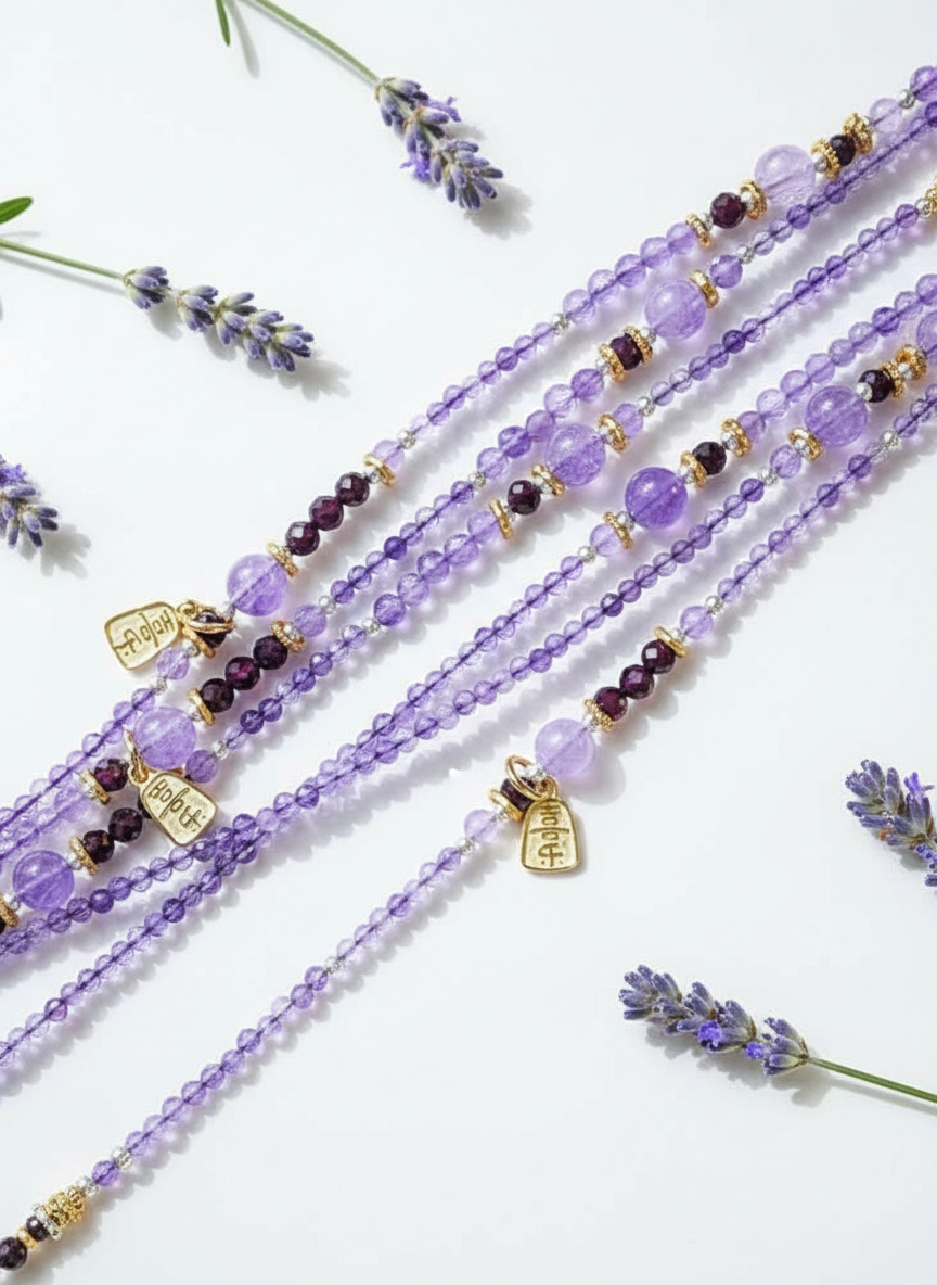 Purple beaded bracelets with charms on a white background with lavender flowers.