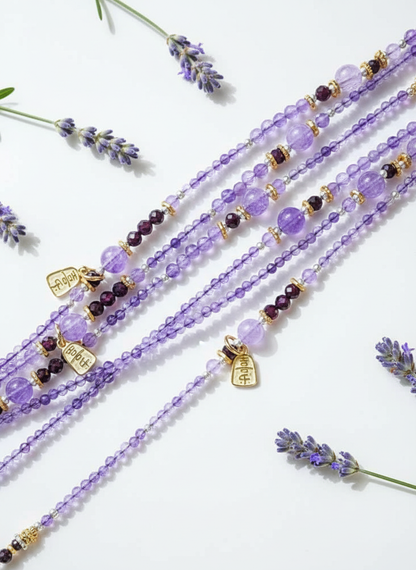 Purple beaded bracelets with charms on a white background with lavender flowers.
