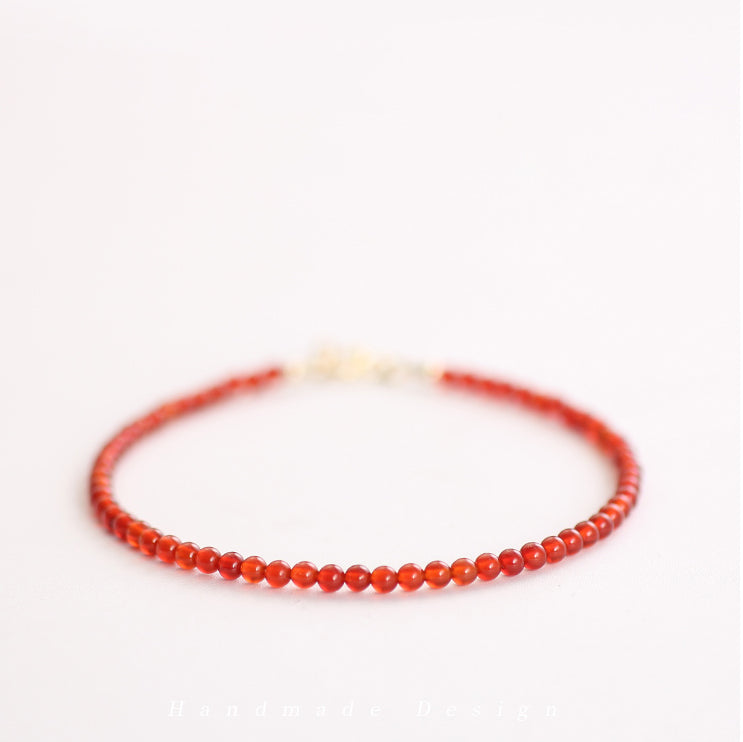 Thin red beaded bracelet on a white background
