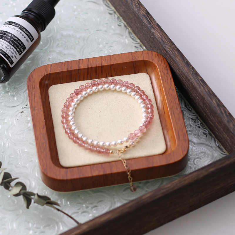 Two bracelets on a wooden tray with a marble background.