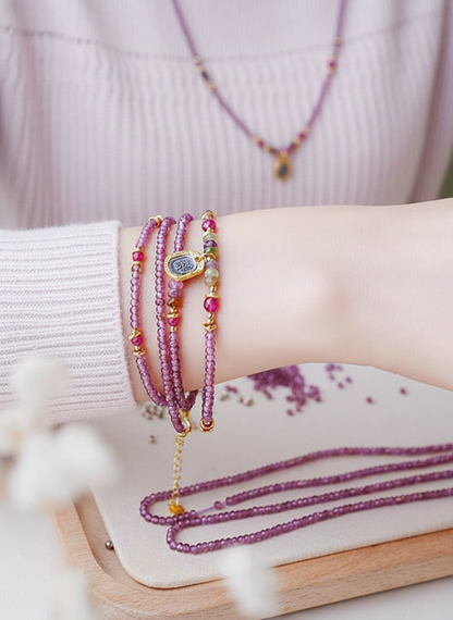 Close-up of a wrist with multiple beaded bracelets on a light background
