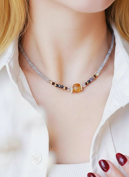 Necklace with multicolored beads worn by a person in a white shirt.
