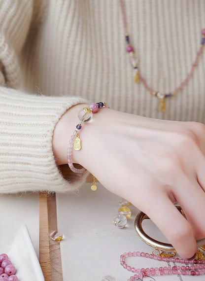 Close-up of a hand wearing a bracelet with beads, set against a neutral background.