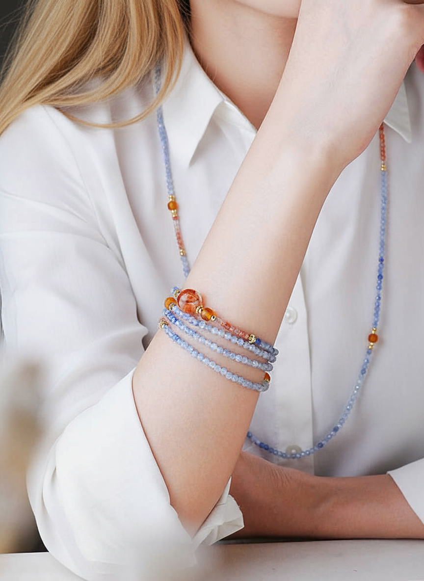 Person wearing a white shirt with colorful beaded bracelets on a plain background