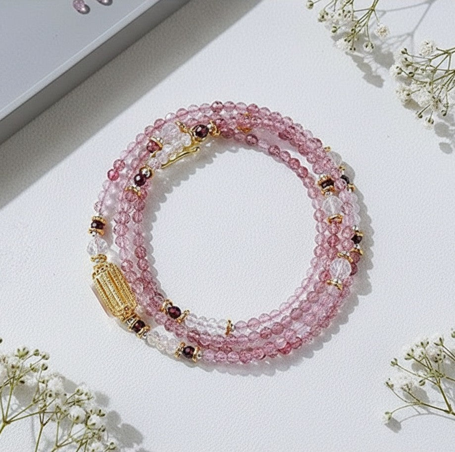 Pink beaded bracelet with gold accents on a white surface with small flowers.