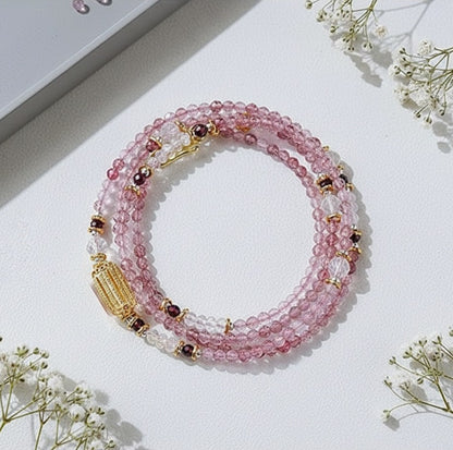 Pink beaded bracelet with gold accents on a white surface with small flowers.