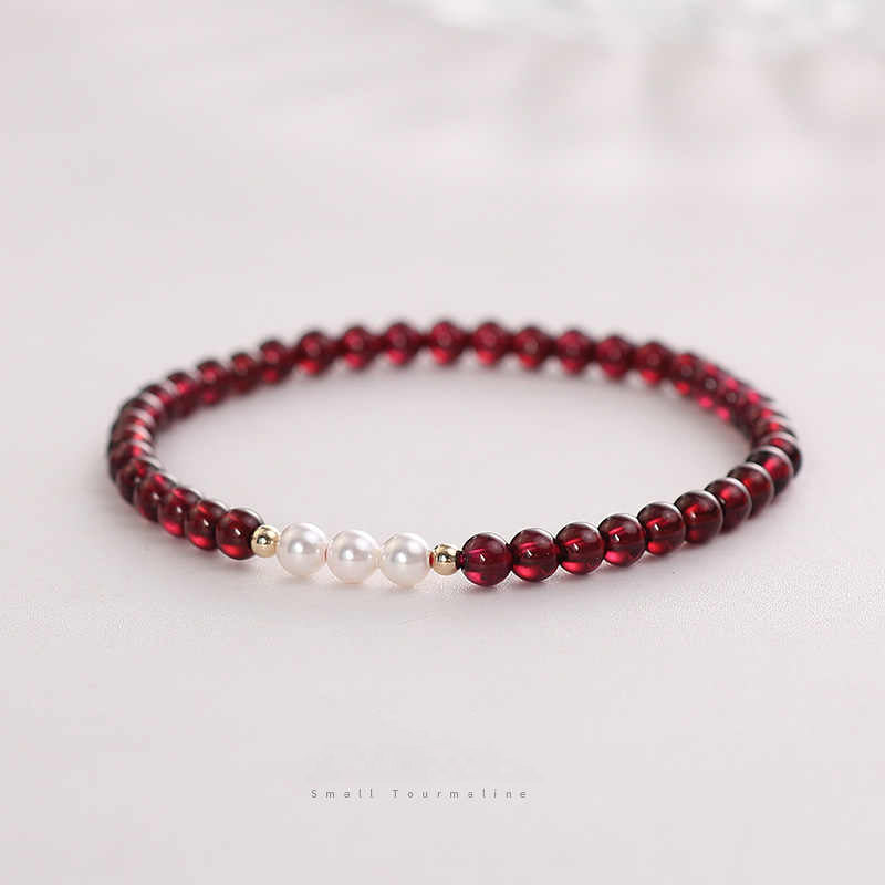 A bracelet with deep red natural garnet beads and white freshwater pearls, with gold-toned spacers and a comfortable elastic fit.
