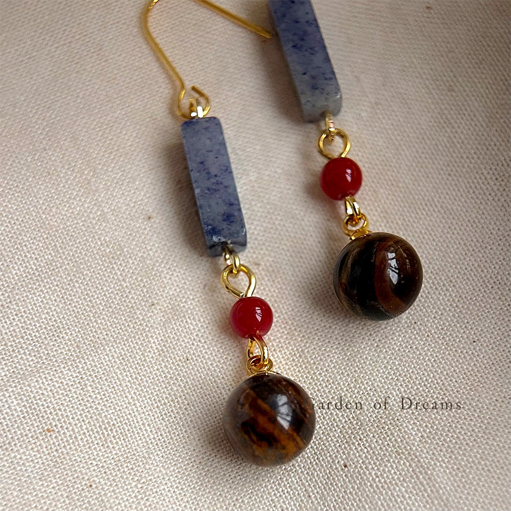 Pair of earrings with beads on a textured fabric background