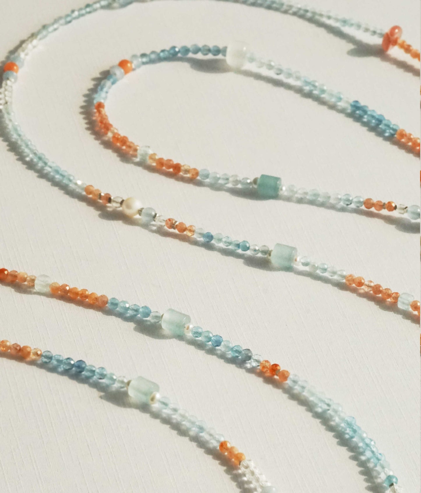 Close-up of a beaded necklace with orange and blue beads on a light background