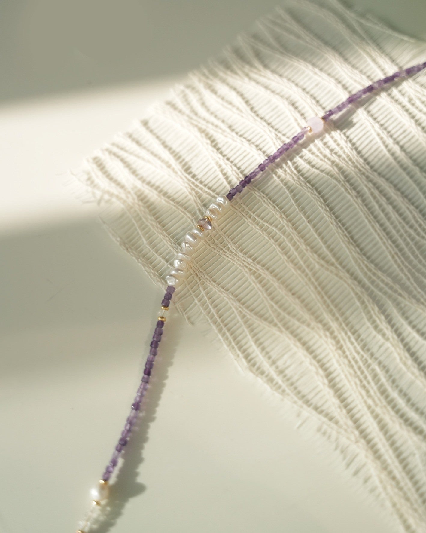 Close-up of a beaded necklace on a textured fabric background