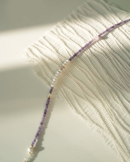 Close-up of a beaded necklace on a textured fabric background