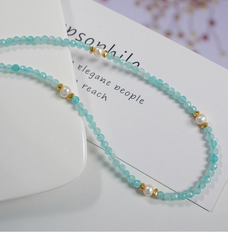 Beaded necklace with turquoise beads and gold accents on a white card with text.