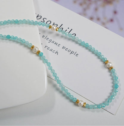 Beaded necklace with turquoise beads and gold accents on a white card with text.