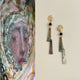 Pair of earrings with gold accents and black beads on a neutral background