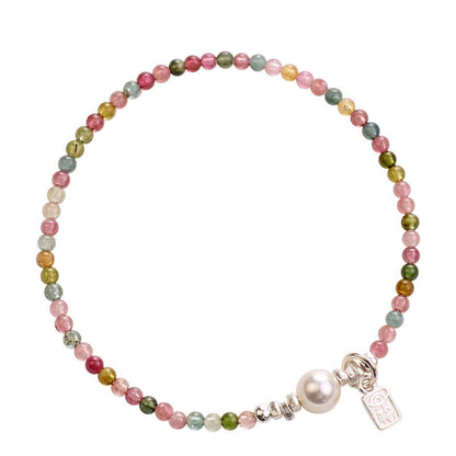 Multicolored beaded bracelet with a pearl charm on a white background