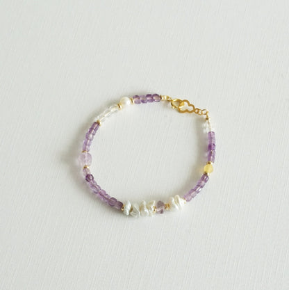 Beaded bracelet with purple and gold accents on a light gray background