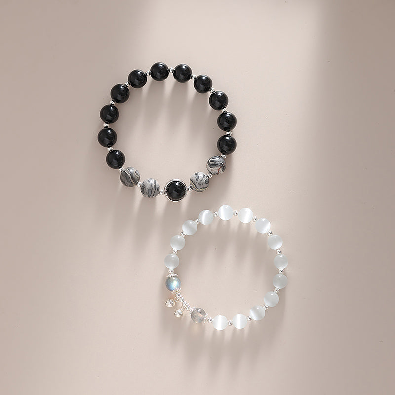 Two bracelets, one black and one white, on a neutral background.